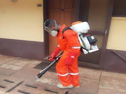 A man dressed in an overall spraying chemicals on the ground in Juba, South Sudan.