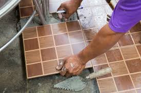 Hands on a man installing tiles on the floor in Juba, South Sudan