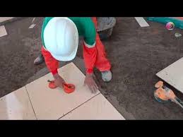 A man bent over aligning tiles on the floor in Juba, South Sudan