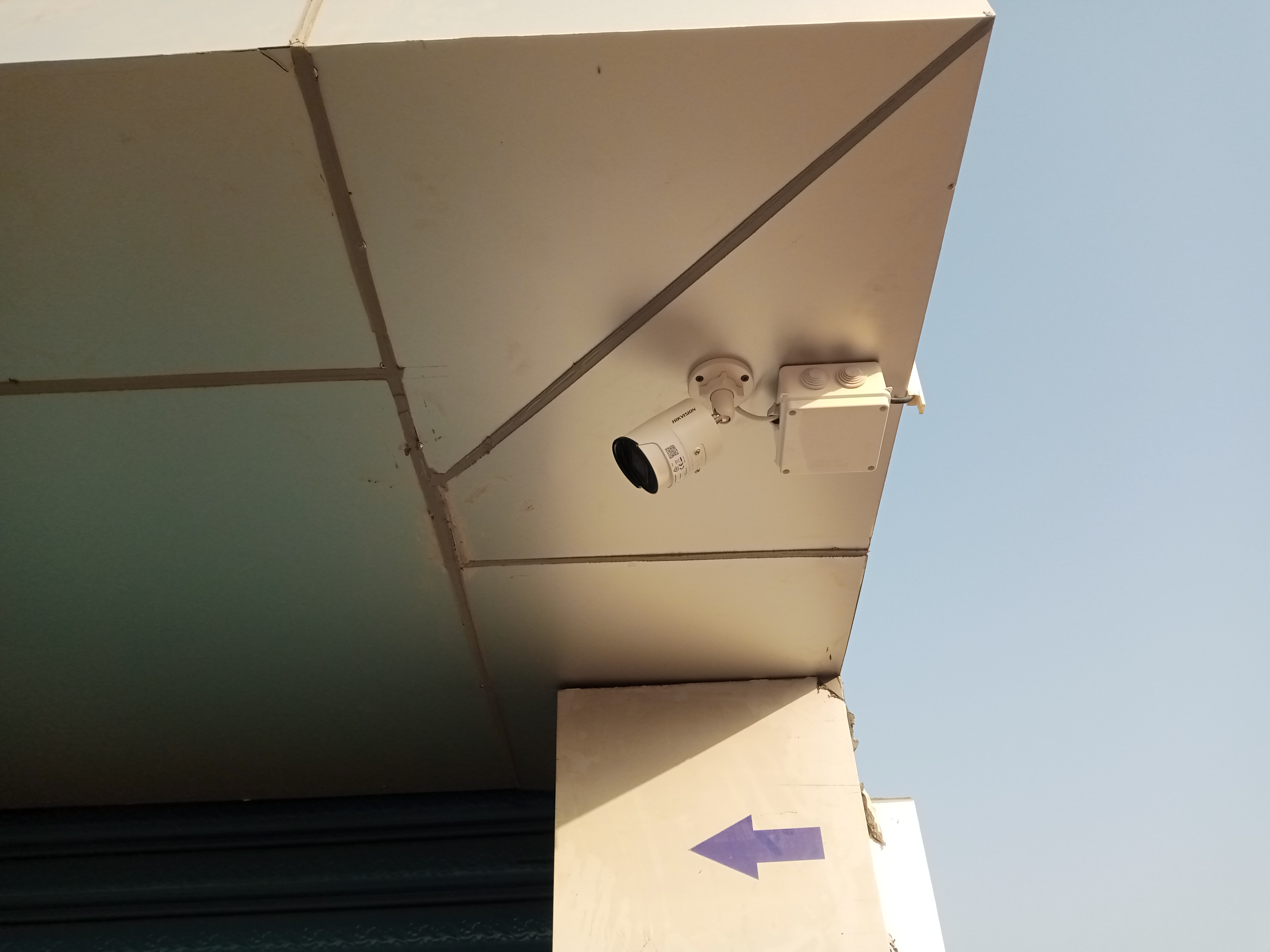 A side view of a bullet camera hanging on an aluminum ceiling