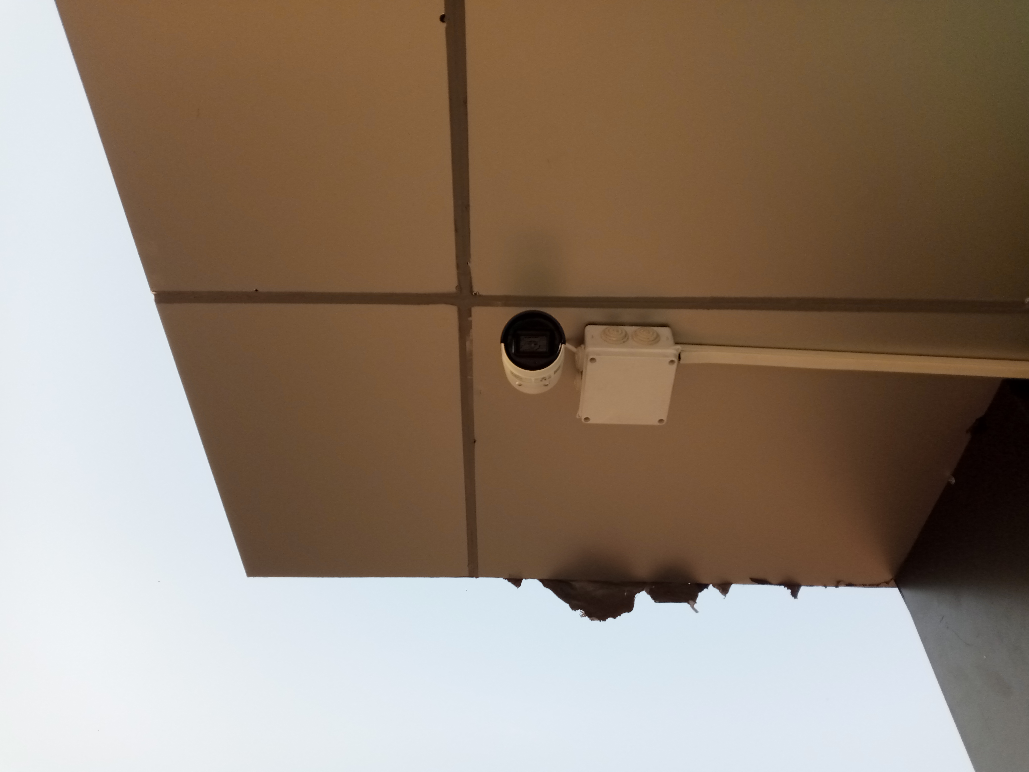 A front view of A bullet camera high up on the ceiling