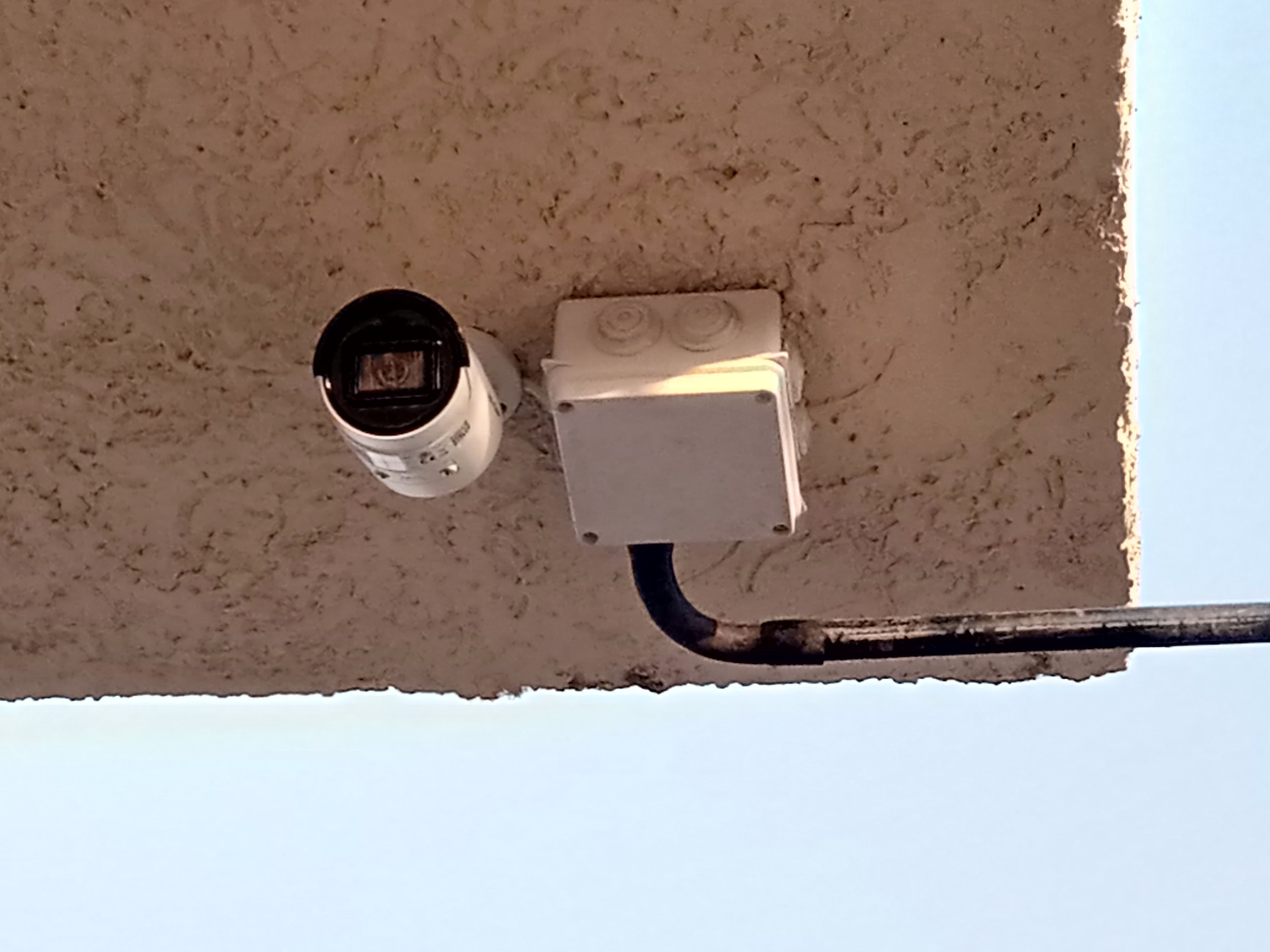 A bullet camera mounted on ceiling with adapter box next to it
