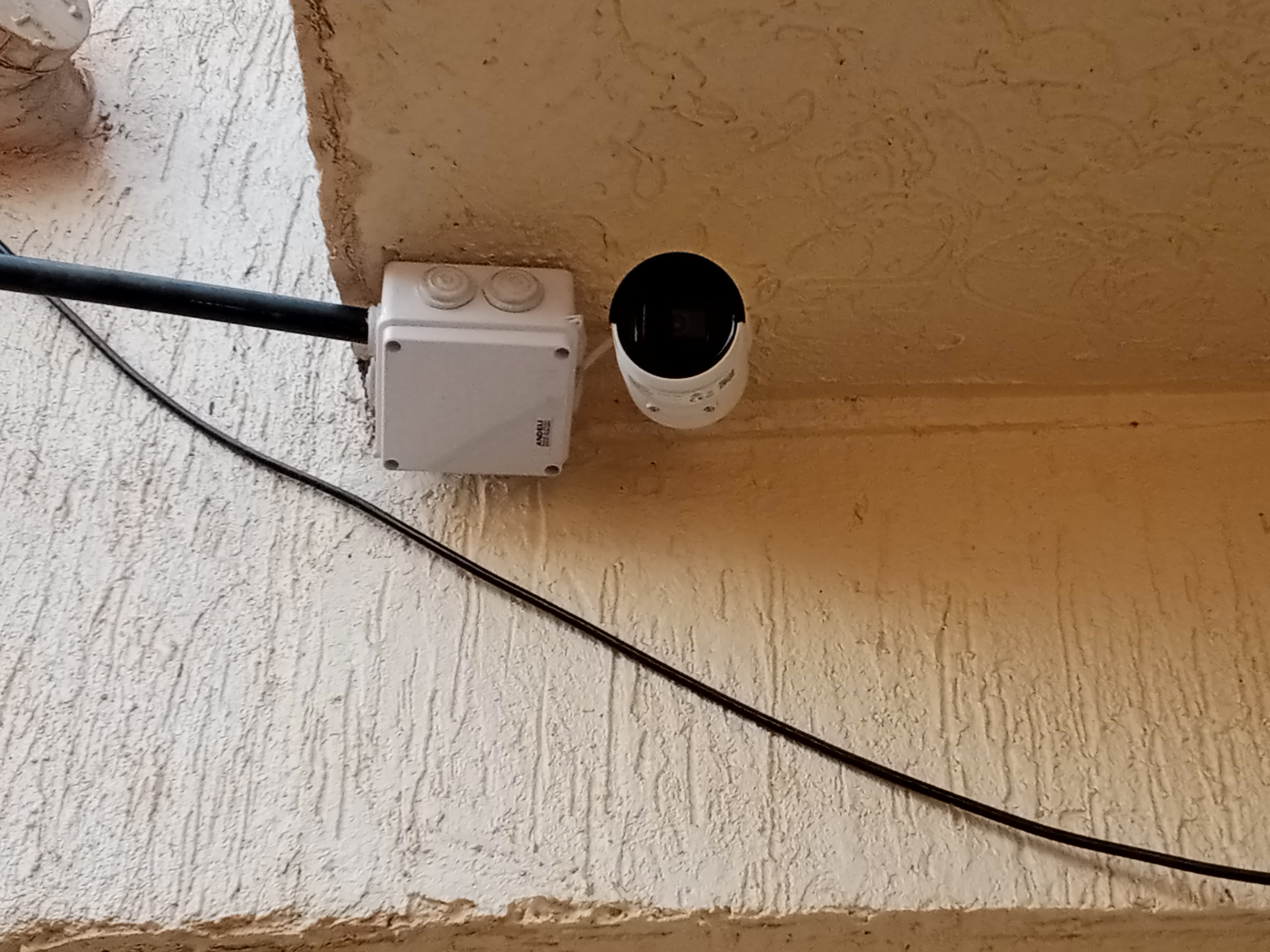 A bullet camer mounted outdoor with an adapter box next it