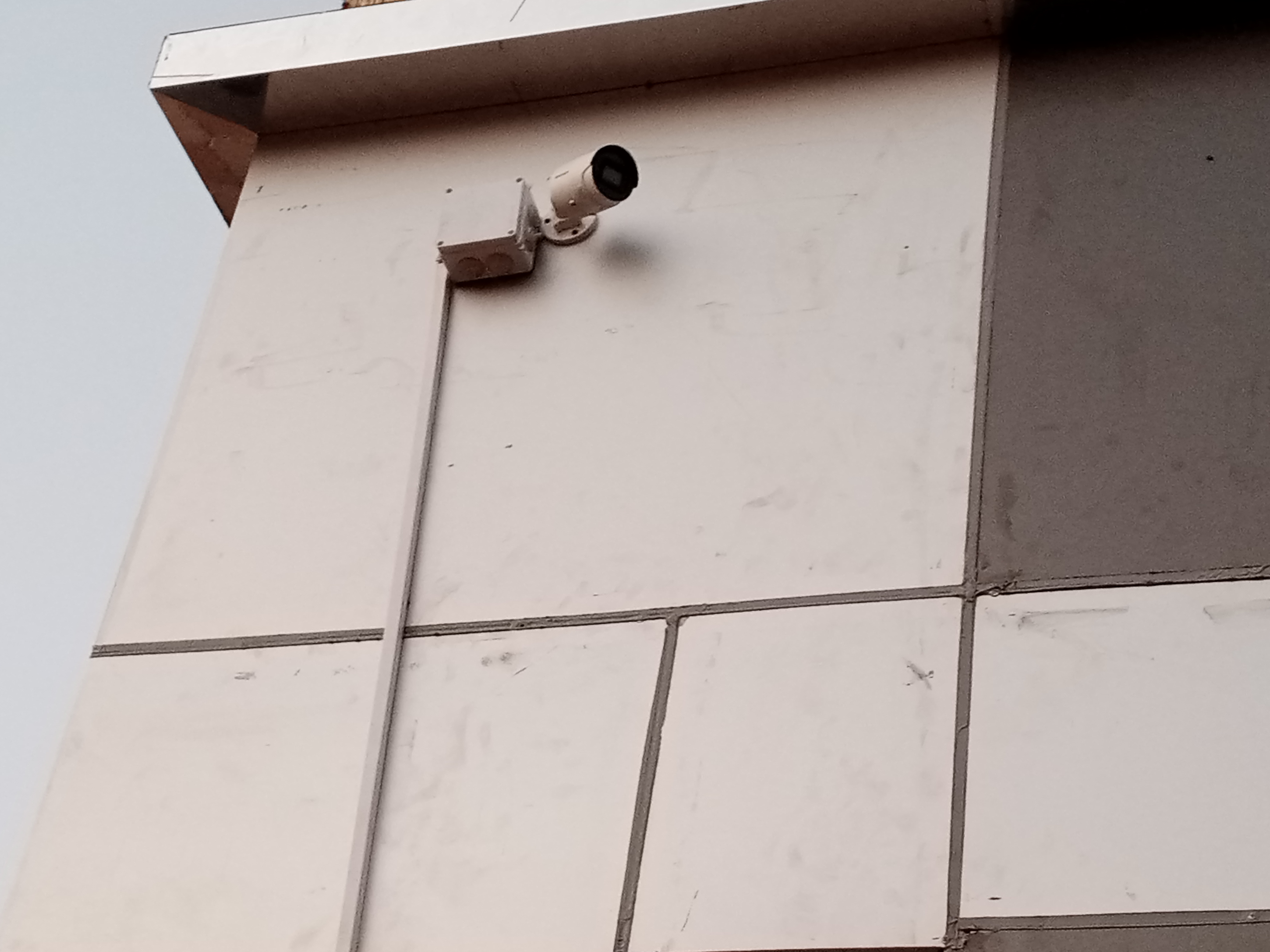 A bullet camera mounted outdoor next to adapter box